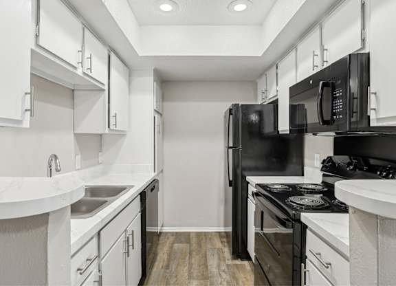 A5 kitchen with black appliances and white cabinets at Windridge on the Parkway apartments in Dallas, TX