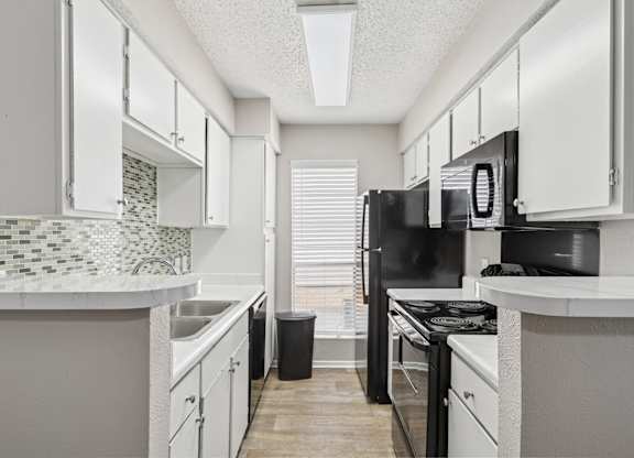 A6 kitchen with black appliances and white cabinets at Windridge on the Parkway apartments in Dallas, TX.