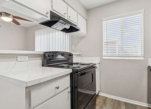 B6 kitchen with a black stove top oven and white cabinets at Windridge on the Parkway in Dallas, TX