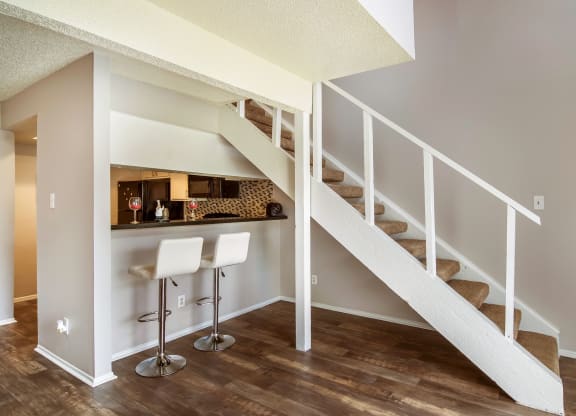 a bar under the stairs in a home with wood floors