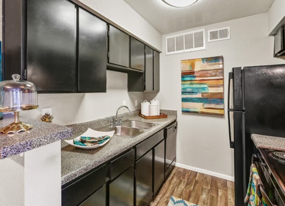 a kitchen with black cabinets, sink and fridge at Bear Creek Crossing apartments in Houston, TX