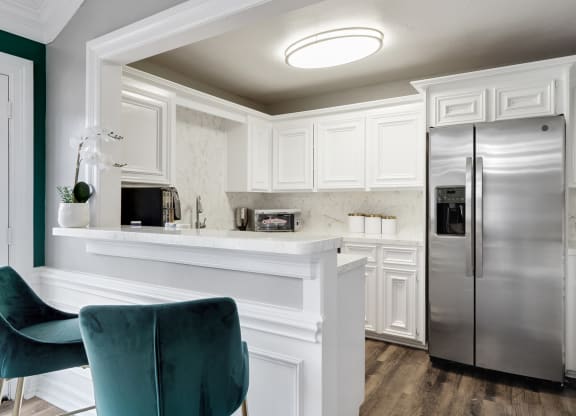 a kitchen with white cabinets and a silver refrigerator