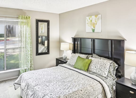 Model apartment bedroom with a bed and a large window at Hunters Chase in Austin, TX