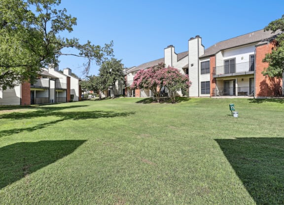 Lush green landscape with pet waste collection stations at Hunters Chase in Austin, TX