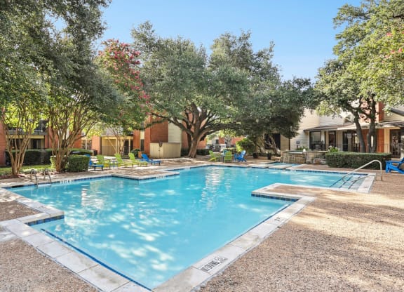 Swimming pool with trees and apartment buildings at Hunters Chase in Austin, TX
