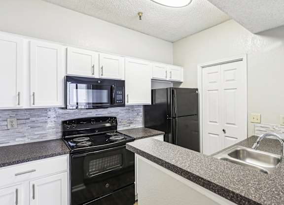 A1 floor plan kitchen with black appliances and elevated counter at Jefferson Creek Apartments in Irving, TX.