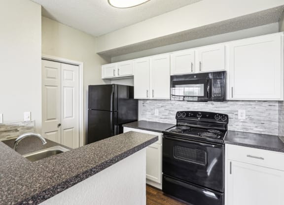 A2 floor plan updated kitchen with black appliances and white cabinets at Jefferson Creek Apartments in Irving, TX.