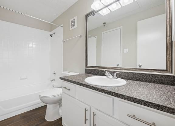 B1 bathroom with a toilet, sink, and mirror at Jefferson Place Apartments in Irving, TX