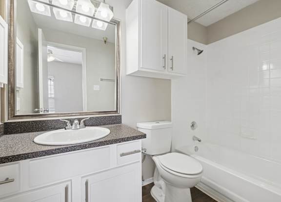 B1 bathroom with white walls, a sink, toilet, and bathtub at Jefferson Place Apartments in Irving, TX