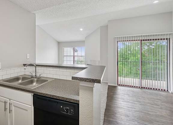B2 kitchen overlooking living room and sliding door to private balcony at Jefferson Place apartments in Irving, TX