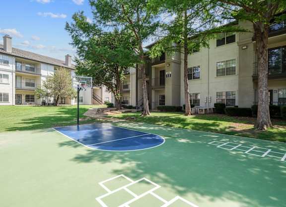 A basketball court and hopscotch area surrounded by apartment buildings at Jefferson Place Apartments in Irving, TX