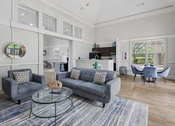 Resident lounge with grey couches, a glass coffee table, and a gray rug at Jefferson Place Apartments in Irving, TX