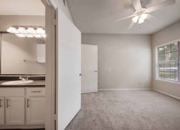 a bedroom with a large window and a ceiling fan