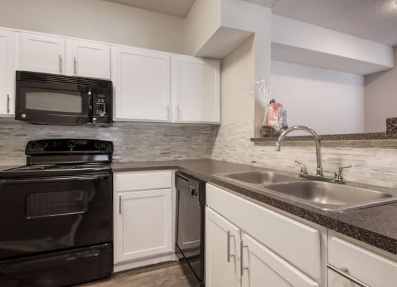 a kitchen with white cabinets and black appliances