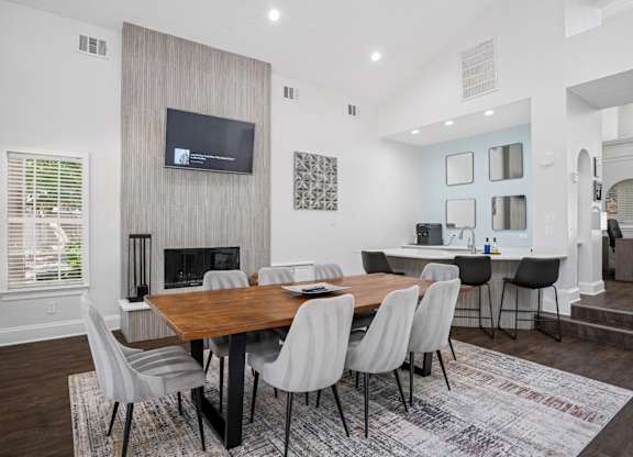 Resident clubhouse with a wooden table and grey chairs.