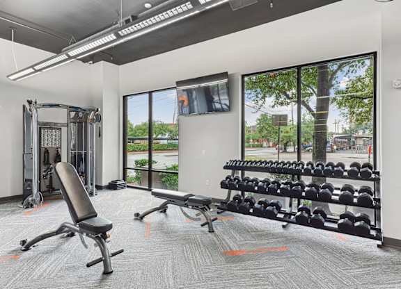 Free weights and workout benches in our state-of-the-art fitness center at Muse at Museum District apartments in Houston, TX