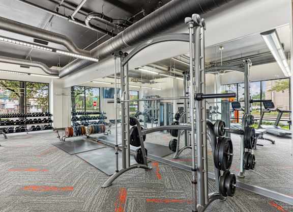 Our gym with a variety of equipment including dumbbells and weight plates at Muse at Museum District apartments in Houston, TX