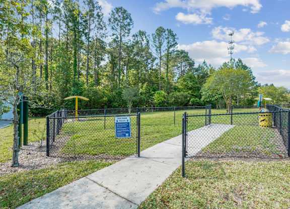 A sign is on a fence in front of a grassy area.