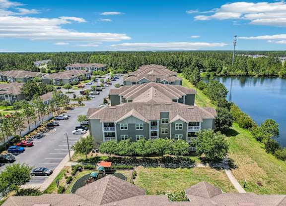 A large house with a green lawn in front of a lake.