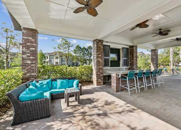 A patio with a couch, chairs, and a table under a roof.