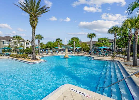 A large pool with a slide and palm trees around it.