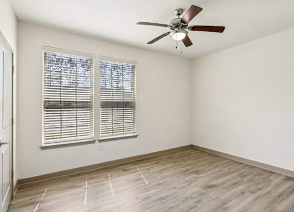 A room with a ceiling fan and a window with blinds.