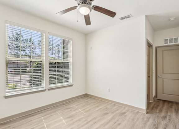 A room with a ceiling fan and a door leading to another room.