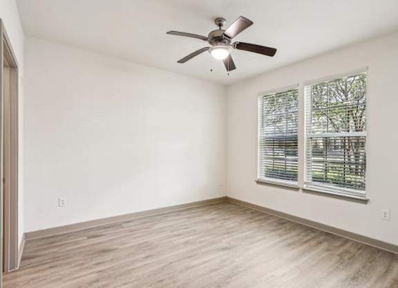 Royal Palm floor plan bedroom with a ceiling fan and a window with blinds at Oakleaf Plantation apartments in Jacksonville, FL.