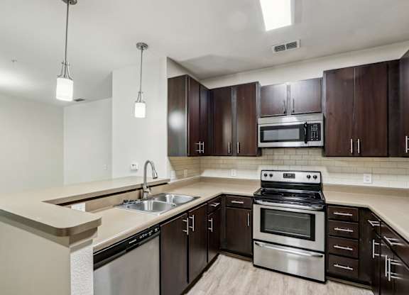 A modern kitchen with dark wood cabinets and stainless steel appliances in the Royal Palm at Oakleaf Plantation Apartments in Jacksonville, FL