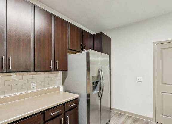 Royal Palm kitchen with brown cabinets and a stainless steel refrigerator at Oakleaf Plantation apartments in Jacksonville, FL.