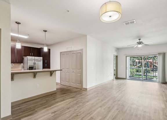 A spacious living room with wooden floors and sliding glass doors that lead to the patio at Oakleaf Plantation Apartments in Jacksonville, FL