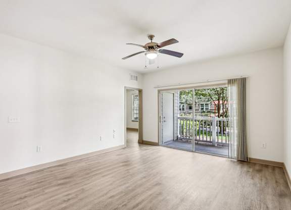 Royal Palm living room with a ceiling fan and sliding glass doors that lead to the patio at Oakleaf Plantation Apartments in Jacksonville, FL