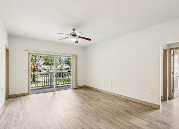 Royal Palm floor plan living room with a ceiling fan and sliding glass doors leading to a patio space at Oakleaf Plantation apartments in Jacksonville, FL.