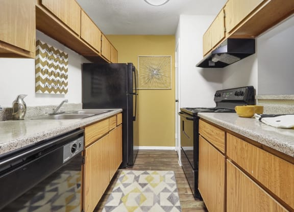 a kitchen with a black refrigerator freezer next to a stove top oven