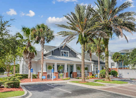 A leasing office with a grey roof is surrounded by palm trees at Wynnfield Lakes Apartments in Jacksonville, FL