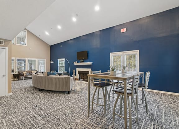 Clubhouse lounge area with couch and a TV above the fireplace at Woodmere Trace apartments in Duluth, GA