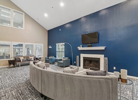 Clubhouse lounge area with couch and a TV above the fireplace at Woodmere Trace apartments in Duluth, GA