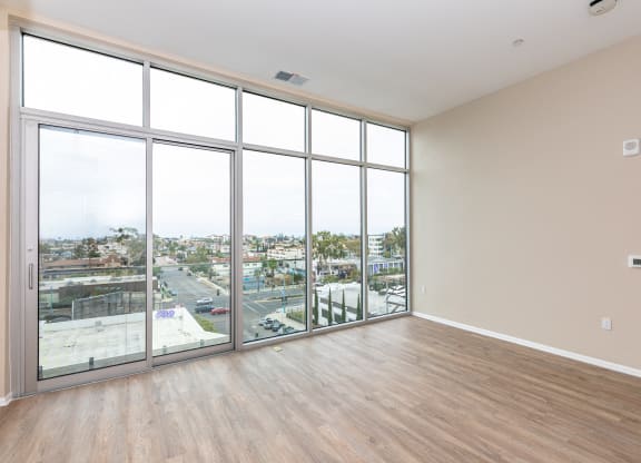 an empty living room with floor to ceiling windows and a city view