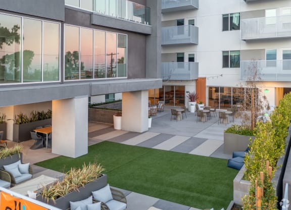 an open courtyard of an apartment building with grass and chairs