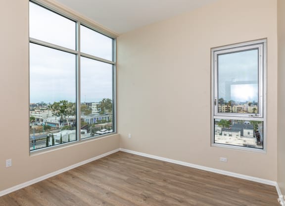 an empty living room with large windows and a city view