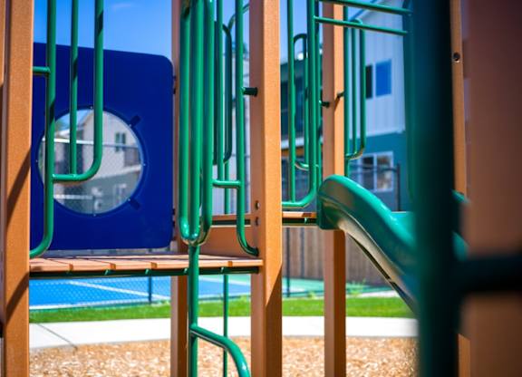 A playground with a blue slide and a green slide.
