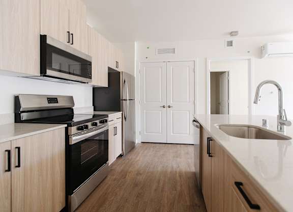 A kitchen with wooden cabinets and a stainless steel sink.