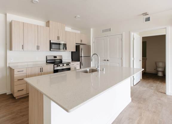 A kitchen with a white countertop and wooden cabinets.