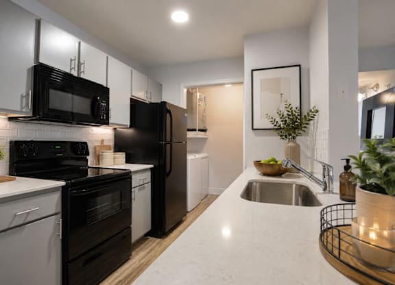 Modern kitchen with black appliances and white countertops at Radius at the Domain Apartments, Austin, Texas