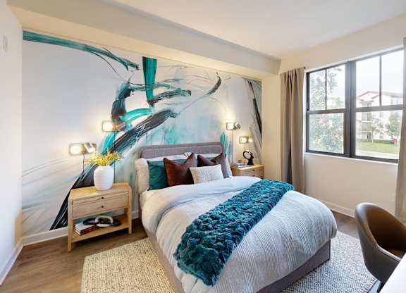 A bedroom with a bed, chair, and a wall art.
