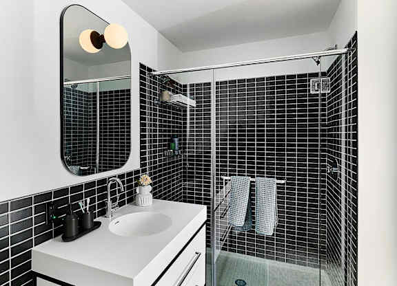 A bathroom with a white sink and black tiles.