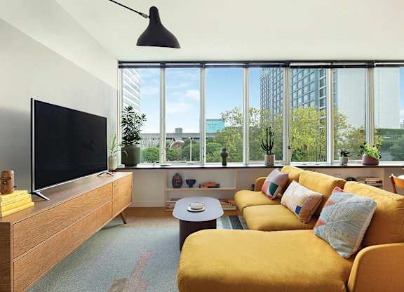 A living room with a yellow couch and a flat screen TV.