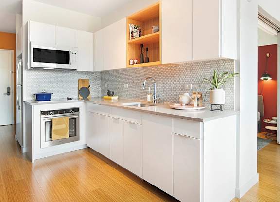 A modern kitchen with white cabinets and a wooden floor.