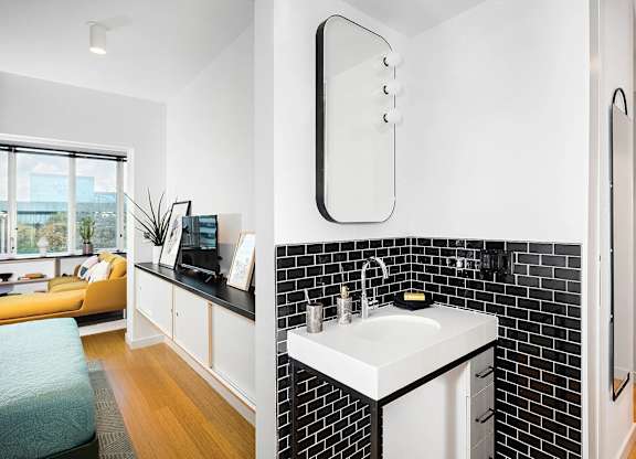 A bathroom with a white sink and black and white tiles.