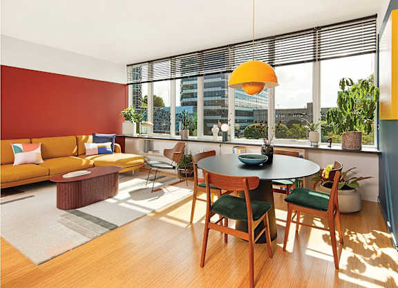 A living room with a red wall and a table with four chairs.